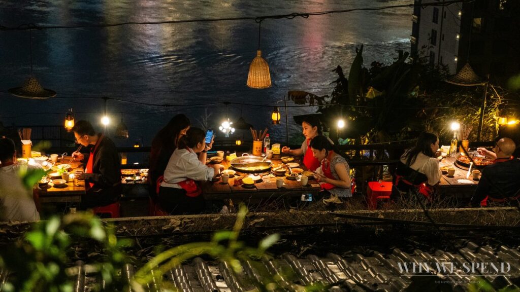 Group of friends dining outdoors at night — social spending pressure