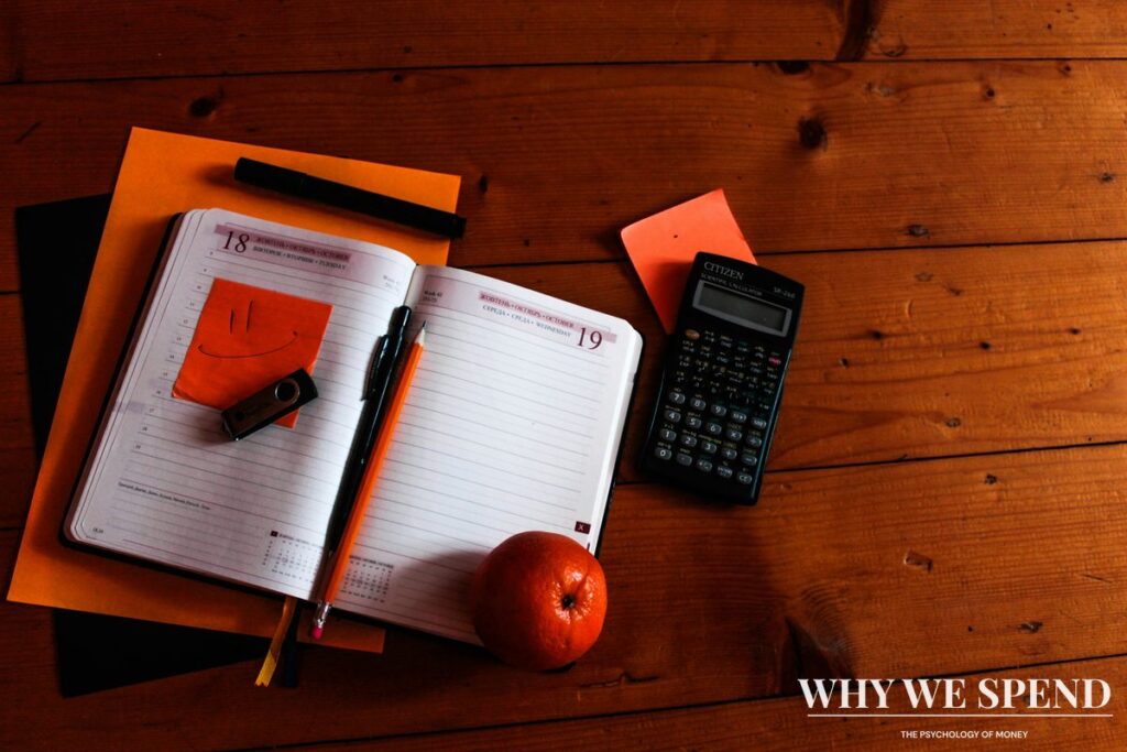 Person planning finances with calculator and notebook showing intentional money management