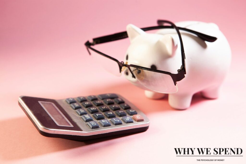 Piggy bank wearing reading glasses slumped over a calculator, symbolising the mental fatigue of tracking expenses.
