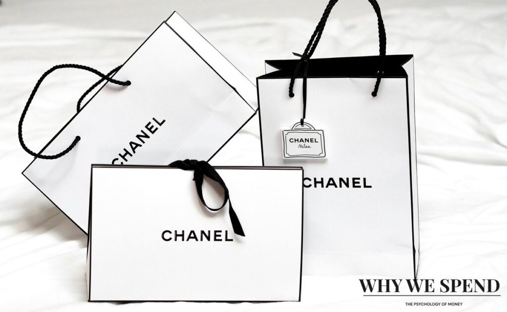 Stack of Chanel shopping bags with ribbon tags, representing luxury purchases driven by celebratory spending.