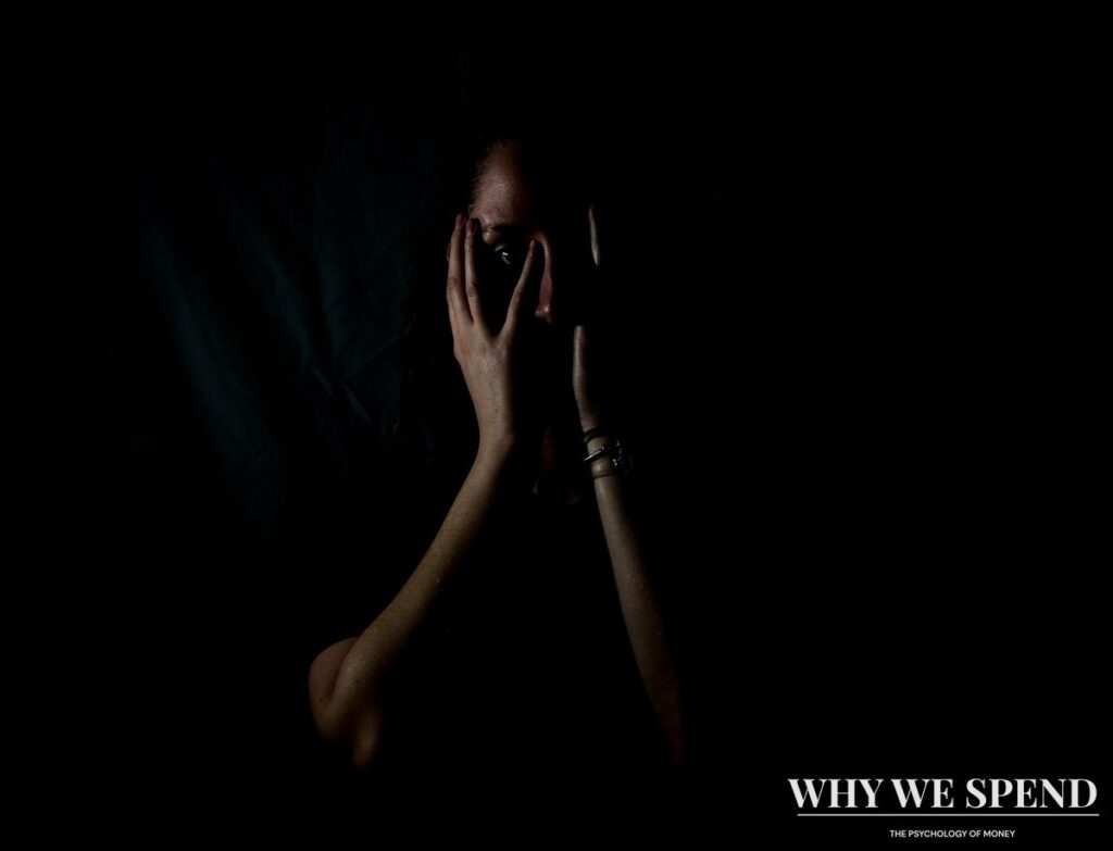 Person sitting alone in shadows representing financial anxiety and isolation
