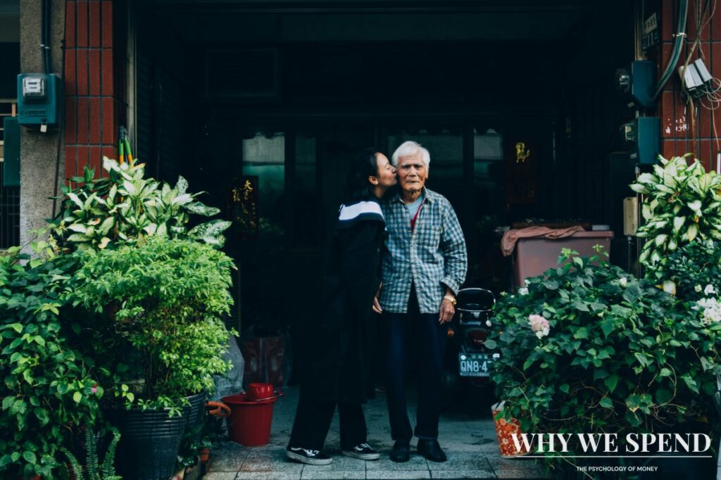 Younger woman kissing an elderly man on the cheek outside their home, representing the close family relationships tied to inheritance expectations.