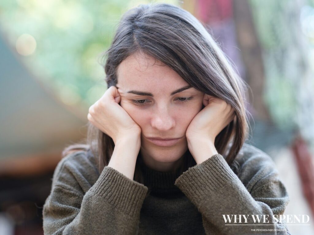 Person looking stressed while checking phone with worried expression about financial decisions