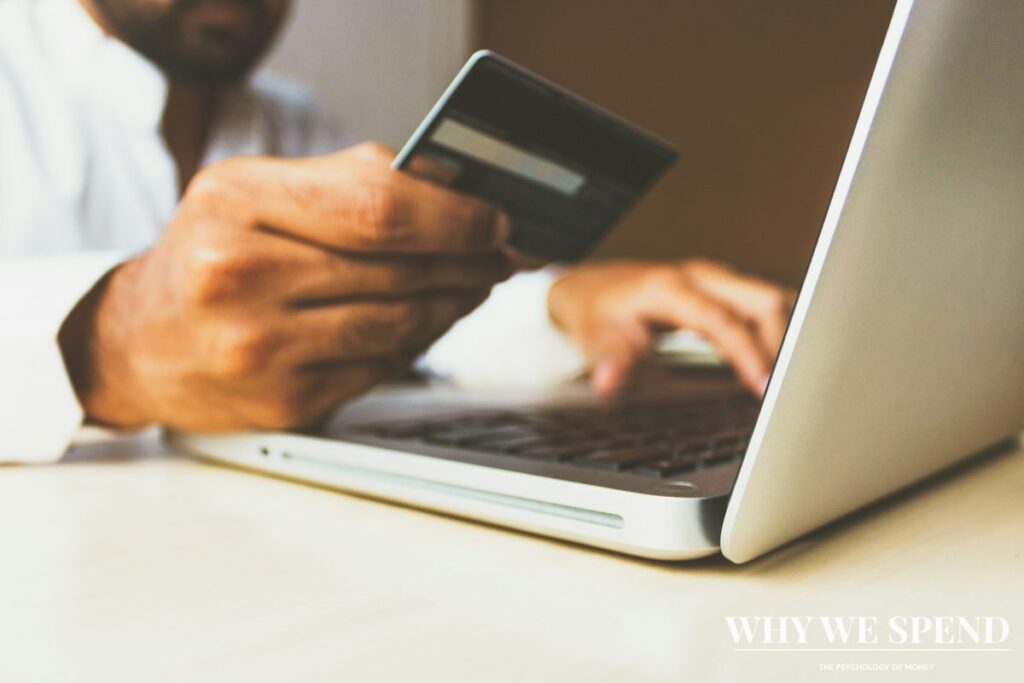 Hand holding credit card in front of laptop for online shopping