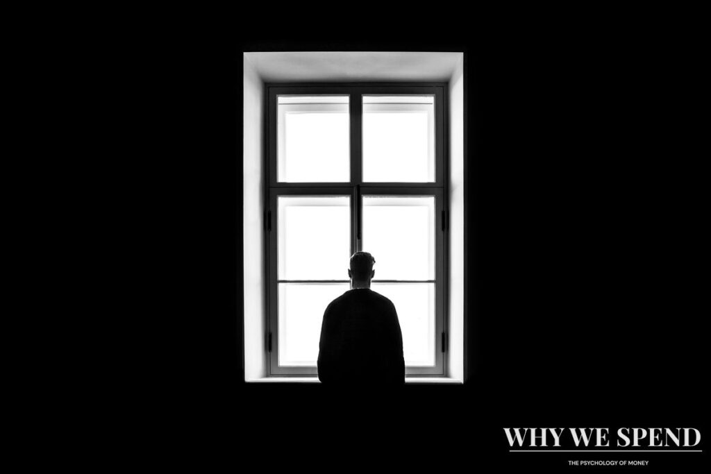Person sitting alone in shadow representing the isolation of keeping money problems secret