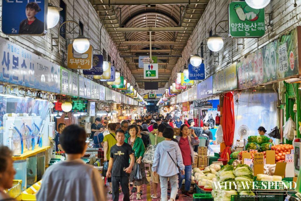 Shopper comparing prices at Asian grocery market stall