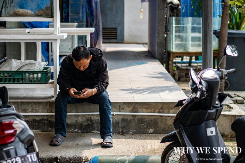 Asian man looking stressed whilst checking financial news on mobile phone