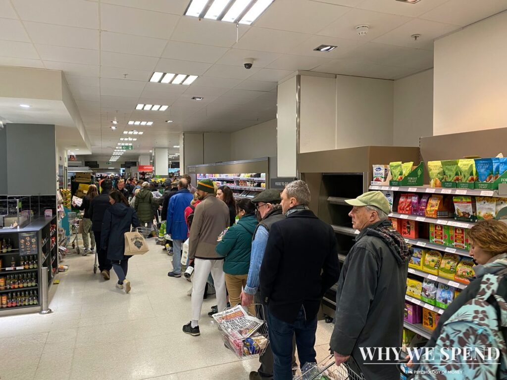 Crowded supermarket checkout queues showing panic buying behaviour during weather warnings